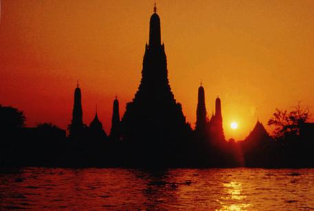 FILE - In this April, 1996, file photo, the sun sets behind the stupa of the Buddhist temple Wat Arun or the "Temple of Dawn" seen from across the banks of the Chao Phraya river in Bangkok, Thailand. Two Americans who maintained a social media account called Traveling Butts have been arrested in Thailand after posting photos of themselves at the famous temple with their rear ends exposed. Deputy police spokesman Krisana Pattanacharoen says the men were arrested Tuesday night at a Bangkok airport and face public indecency charges. (ANSA/AP Photo/Sakchai Lalit, File)