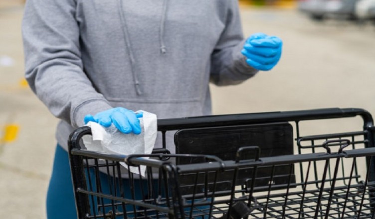 Customer Wipes Down Handles of Grocery Cart