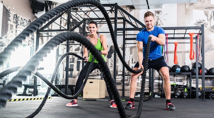 Men with battle rope in functional training fitness gym
