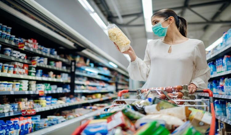Young person with protective face mask buying groceries/supplies in the supermarket.Preparation for a pandemic quarantine due to coronavirus covid-19 outbreak.Choosing nonperishable food essentials