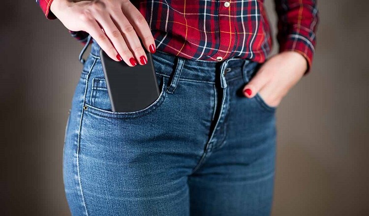 girl puts or takes out a phone in a black case from her pocket, close up