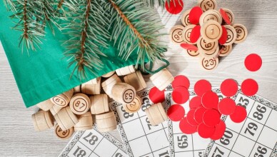 Board game lotto. Wooden lotto barrels with bag, game cards and red chips for a game in lotto, Christmas fir tree branches. Top view